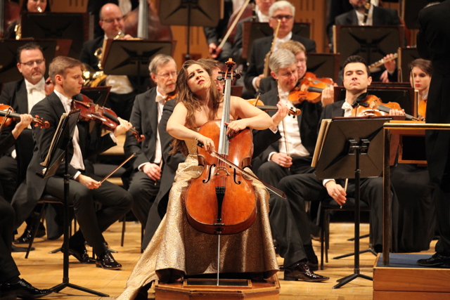 Alisa Weilerstein with her cello on the NCH stage with an orchestra in the background