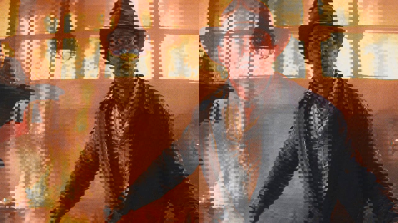 Still image from Raiders of the Lost Ark film with Harrison Ford - a man dressed in a leather jacket against a fire backdrop