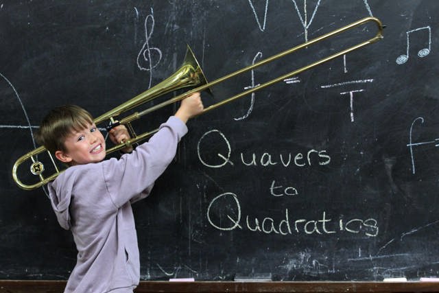 Boy with a trombone in front of a chalkboard