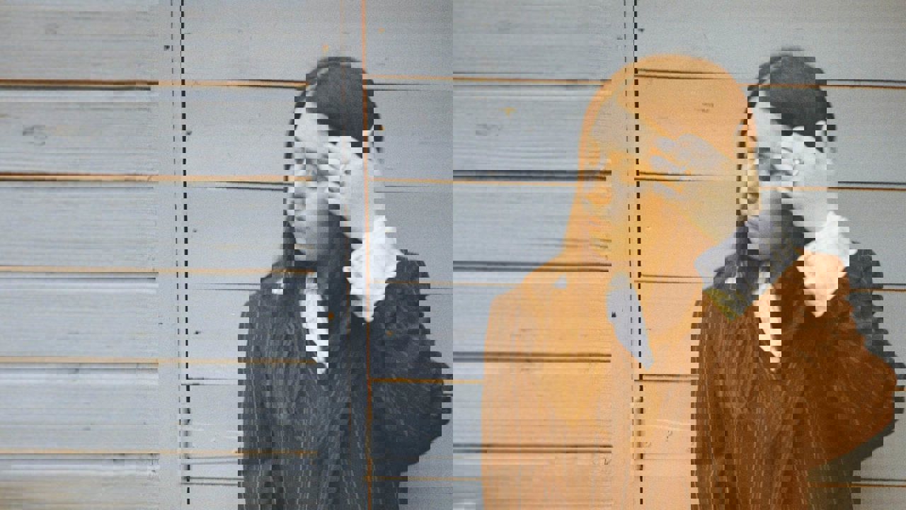 Sorcha - out of focus close-up of a woman in a pinstripe suit against a grey fence