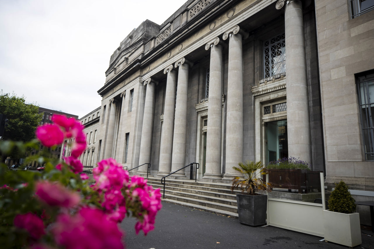 Outdoor image of front entrance to NCH with pink flowers at left of image