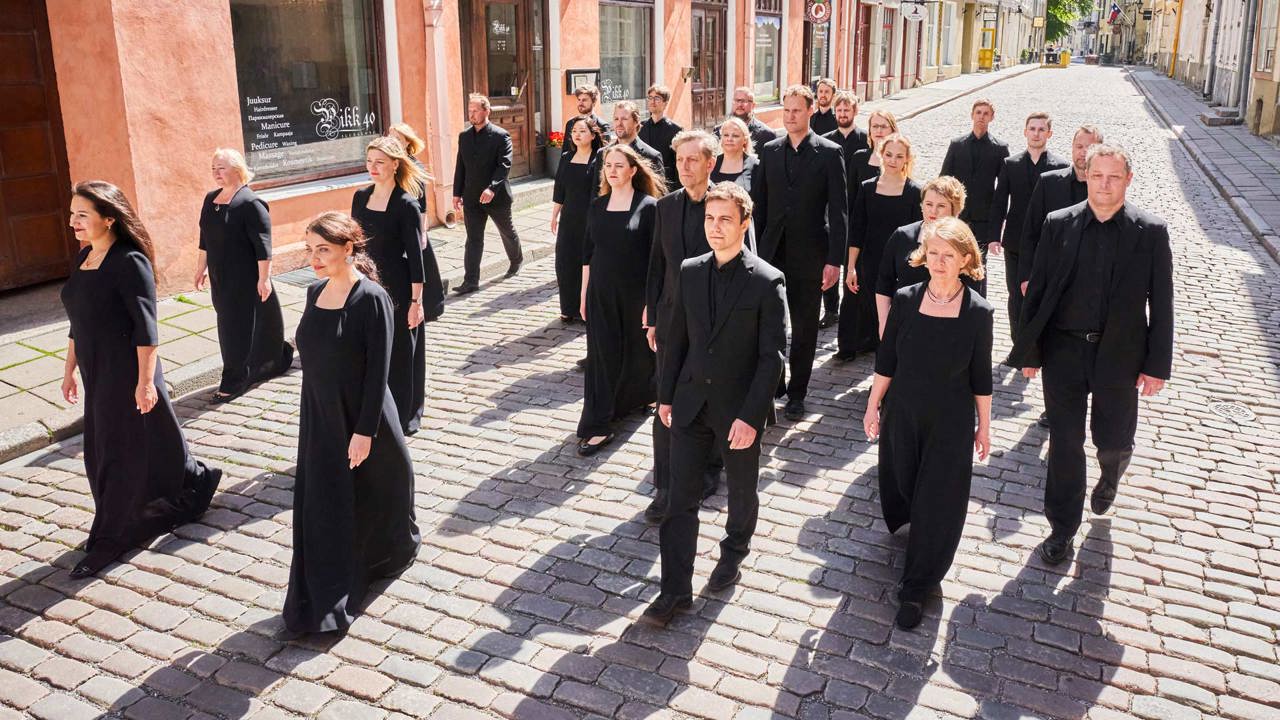 Estonian Philharmonic Chamber Choir - choir members dressed in black walking along a cobbled street with shops in the background