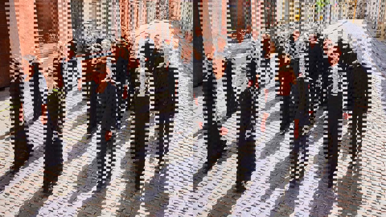 Estonian Philharmonic Chamber Choir - choir members dressed in black walking along a cobbled street with shops in the background