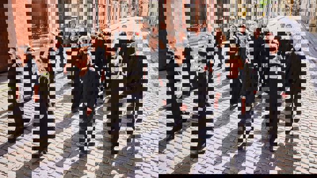 Estonian Philharmonic Chamber Choir - choir members dressed in black walking along a cobbled street with shops in the background