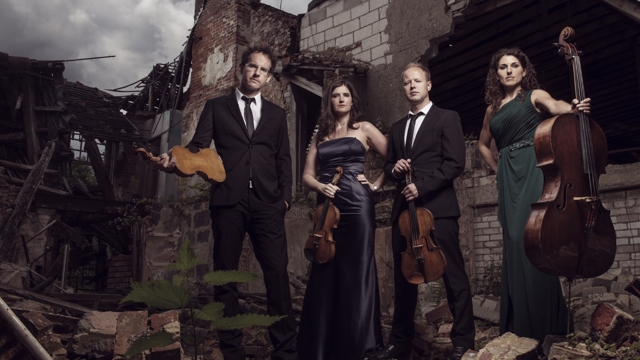 Carducci Quartet - Two men, two women against a demolished house background holding string instruments